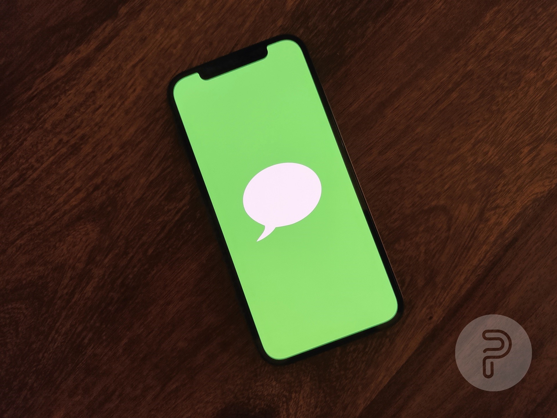 un iPhone colocado sobre una mesa que muestra una imagen con un fondo verde y un globo de diálogo en el medio