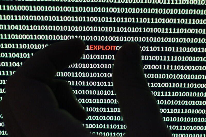 La foto muestra un escáner de seguridad extrayendo un virus de una cadena de código binario.  mano con la palabra 