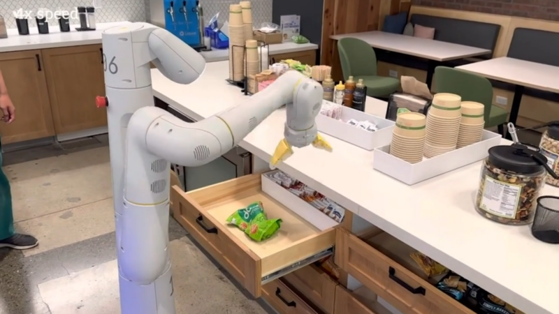 Un brazo robótico controlado por PaLM-E agarra una bolsa de papas fritas en un video de demostración.