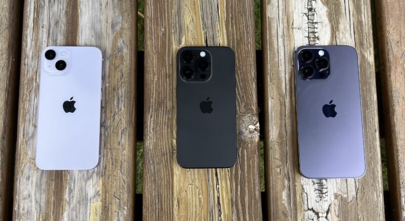 Tres iPhones en un banco de picnic de madera, con las cámaras a la vista